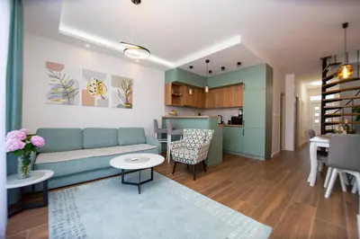 a living room with a blue couch and a kitchen at Apartment Sara with seaview in Budva