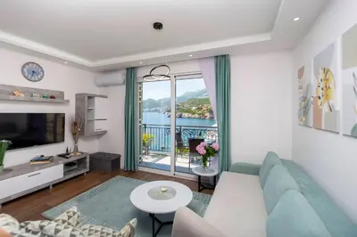 a living room with a blue couch and a large window at Apartment Sara with seaview in Budva