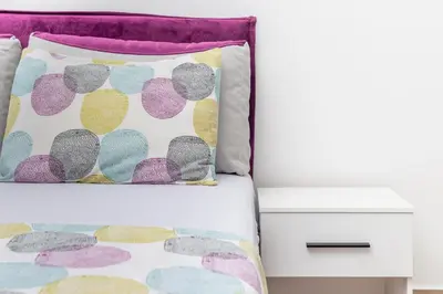 a bed with a colorful pillow and a nightstand at Studio apartman Scardona in Kotor