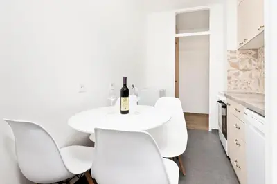 a white kitchen with a white table and white chairs at Studio apartman Scardona in Kotor
