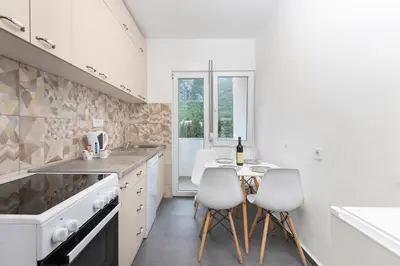 a kitchen with white appliances and a table with white chairs at Studio apartman Scardona in Kotor