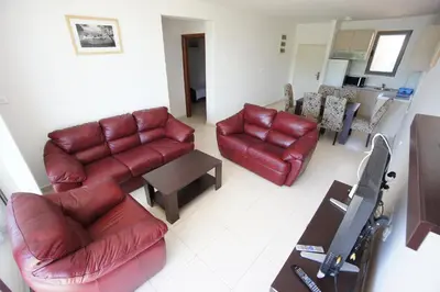 a living room with red leather furniture and a television at Apartments Bečići Sunset in Budva