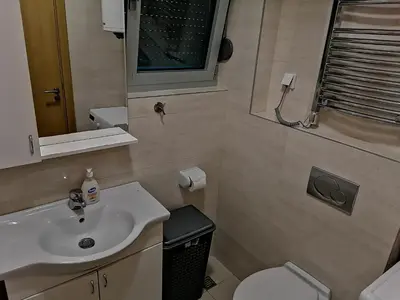 a bathroom with a sink and a toilet and a mirror at Apartman Sara in Pržno