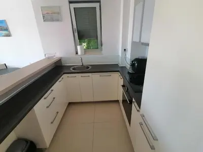 a small white kitchen with a sink and a window at Apartman Sara in Pržno