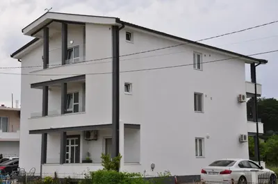 a white building with a car parked in front of it at Heaven Home in Ulcinj