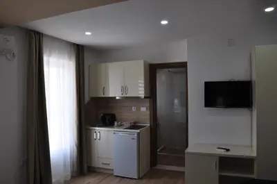 a small kitchen with white cabinets and a television at Heaven Home in Ulcinj