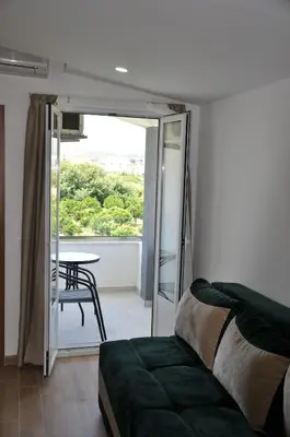 a bedroom with a bed and a table and a balcony at Heaven Home in Ulcinj
