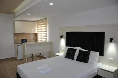 a bedroom with a large white bed and a kitchen at Heaven Home in Ulcinj