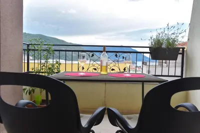 a table with glasses and a bottle of wine on a balcony at Full of light, relaxing, calming apartment in BD in Budva