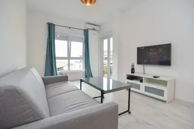 a living room with a couch and a tv at Full of light, relaxing, calming apartment in BD in Budva
