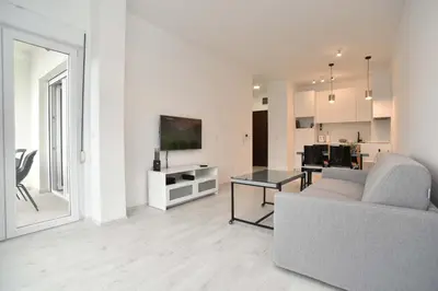 a white living room with a couch and a table at Full of light, relaxing, calming apartment in BD in Budva