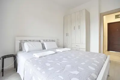 a white bedroom with a large white bed in it at Full of light, relaxing, calming apartment in BD in Budva