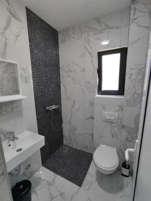 a white bathroom with a toilet and a sink at Horizont Dobre Vode in Dobra Voda