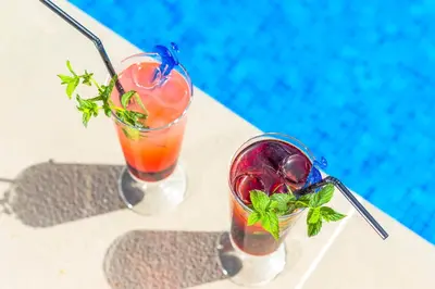 two cocktails sitting on a table next to a pool at Dekaderon Lux Apartments in Kotor
