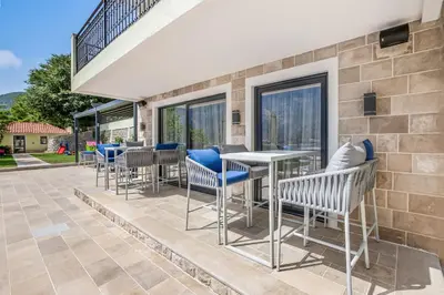 a patio with chairs and tables and windows at Dekaderon Lux Apartments in Kotor