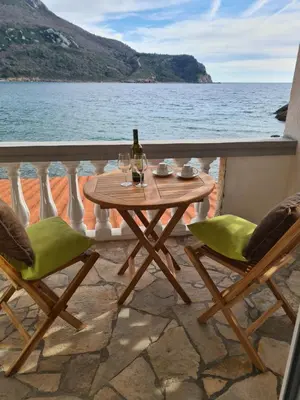a table with a bottle of wine and two chairs at Apartments Zec in Čanj