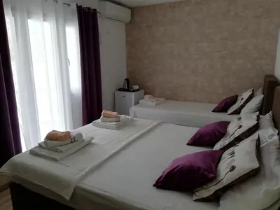 two beds in a room with purple and white pillows at Apartments Zec in Čanj