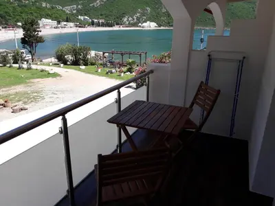 a table and chair on a balcony with a view of the beach at Apartments Zec in Čanj
