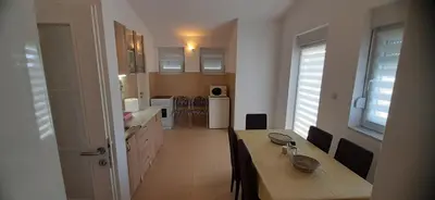 a kitchen with a wooden table and a dining room at Apartmani Paradise in Sutomore