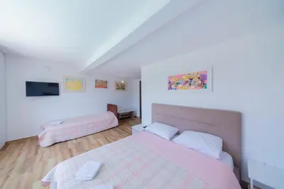 a bedroom with a pink bed and a tv at The Rock Star's Villa with Private Pool and Beach in Danilovgrad