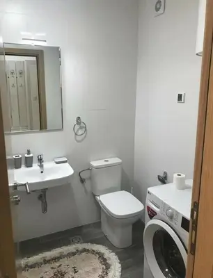 a bathroom with a toilet and a sink and a washing machine at KENZA jednosobni stanovi in Podgorica