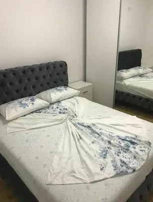 a bedroom with a bed with a headboard and a mirror at KENZA jednosobni stanovi in Podgorica