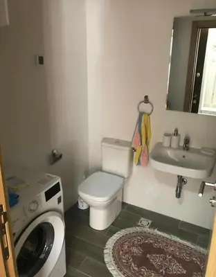 a bathroom with a toilet and a sink and a washing machine at KENZA jednosobni stanovi in Podgorica