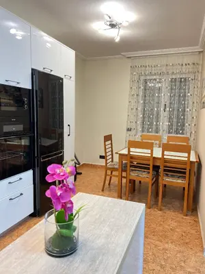 a kitchen and dining room with a table with pink flowers at Vista Petrovac in Petrovac na Moru