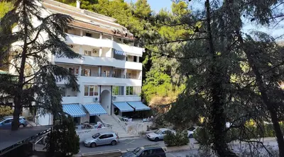 a large white building with cars parked in a parking lot at Vista Petrovac in Petrovac na Moru