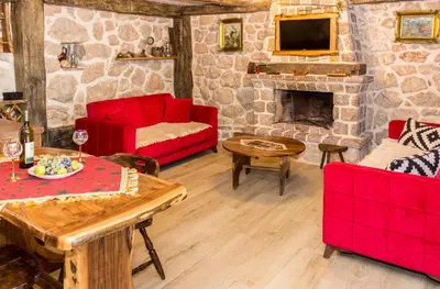 a living room with red furniture and a stone fireplace at Old stone house with swimming pool Etno House Perazic in Bar