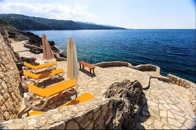 a group of chairs and umbrellas next to the water at Аpartment 555 in Dobra Voda