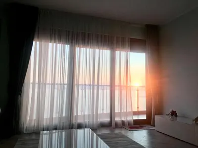 a room with a large window with white curtains at Аpartment 555 in Dobra Voda