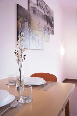 a wooden table with plates and a vase of flowers on it at Apartments Đurović in Petrovac na Moru