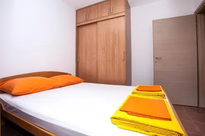 a bed with orange pillows and a yellow object on it at Apartments Đurović in Petrovac na Moru