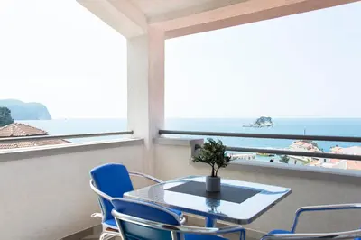 a table and chairs in a room with a view of the ocean at Apartments Đurović in Petrovac na Moru