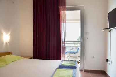 a bedroom with a bed and a window with a chair at Apartments Đurović in Petrovac na Moru