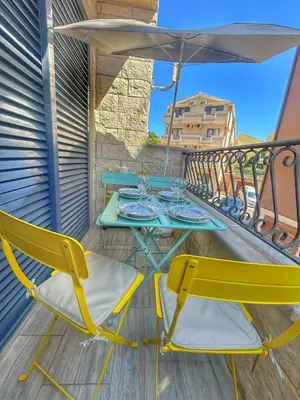 a table and chairs on a balcony with an umbrella at Petrovac Sea in Petrovac na Moru