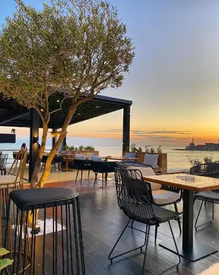 a patio with tables and chairs and the ocean at Petrovac Sea in Petrovac na Moru