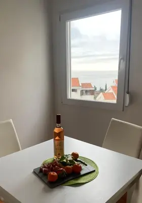 a bottle of wine sitting on a table with a plate of food at Two-bedroom apartment with parking and sea view in Becici