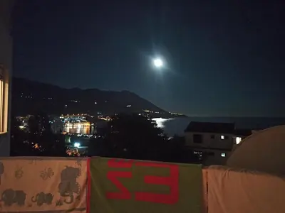 a view of the moon over a city at night at Two-bedroom apartment with parking and sea view in Becici
