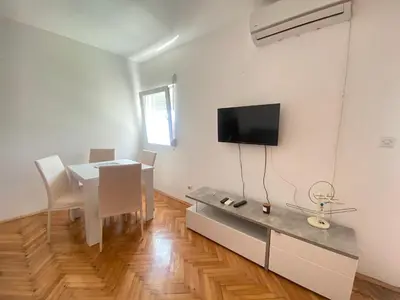 a dining room with a table and a tv on a wall at Two-bedroom apartment with parking and sea view in Becici