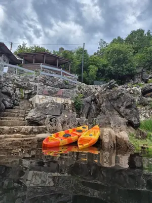 three kayaks are sitting on the water next to some rocks at Old house, Skadar Lake in Cetinje