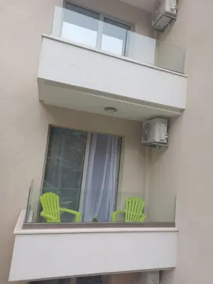 two green chairs on a balcony with a window at Becici stan in Budva