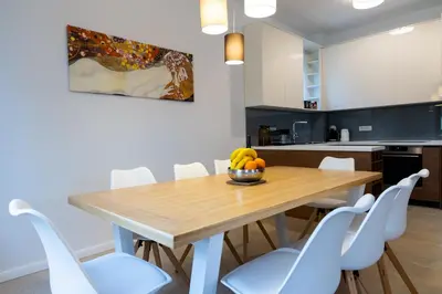 a kitchen and dining room with a wooden table and white chairs at Villa Forte Mare in Petrovac na Moru