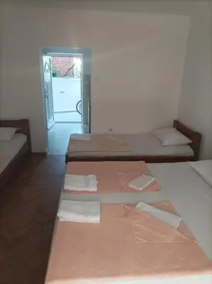 a room with three beds in it with a door at Apartmani Baštrica in Budva