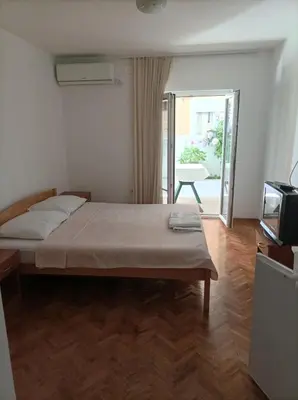 a bedroom with a bed and a television and a balcony at Apartmani Baštrica in Budva