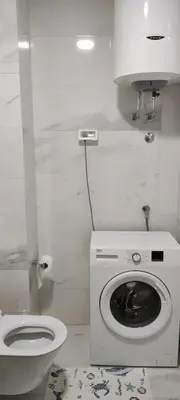 a white bathroom with a toilet and a washing machine at Todor apartment in Bar