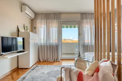 a living room with a television and a large window at Cozy studio in Petrovac with sea view in Petrovac na Moru