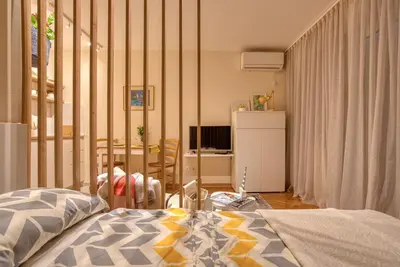 a bedroom with a bed and a room with a desk at Cozy studio in Petrovac with sea view in Petrovac na Moru