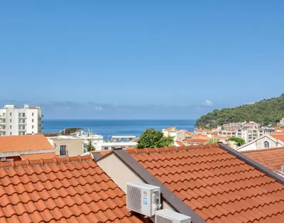 a city with red roofs and the ocean in the background at Cozy studio in Petrovac with sea view in Petrovac na Moru